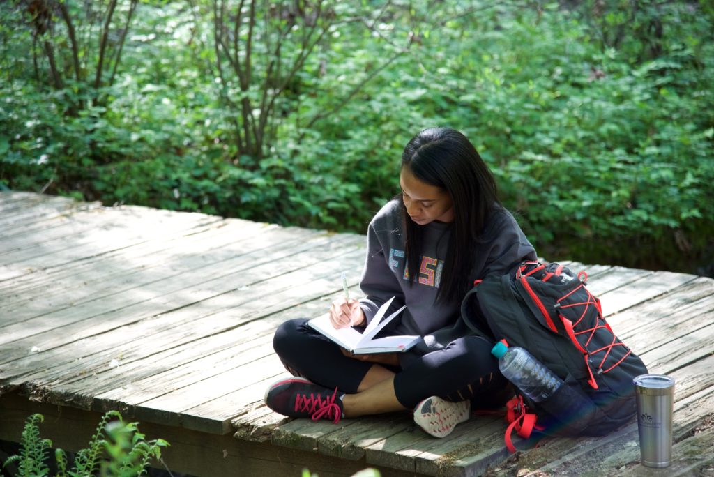 student writing in journal in Botanical Gardens